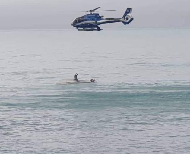 A rescue helicopter circling the upturned boat in Goose Bay, Kaikoura, yesterday. Photo: Supplied
