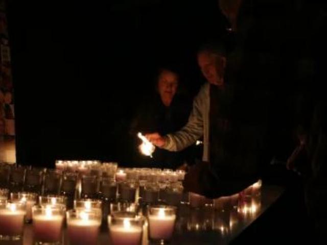 Kim Annan (centre) lights a candle for Stephen Wright with other friends and family members....