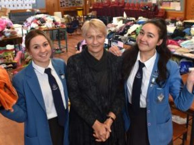 Queen's High School year 13 pupils Anastasia Manza (left) and Grace Parkes with principal Di Carter in the donation space set up in the school's hall. Photo by Gregor Richardson.