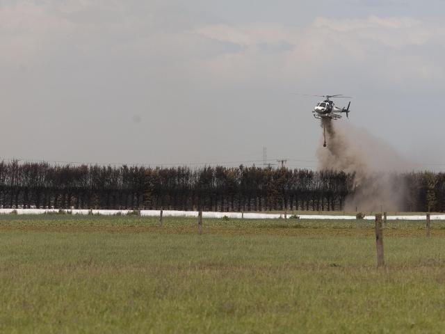 A helicopter with a monsoon bucket fighting a fire near Dunsandel. Photo: Geoff Sloan