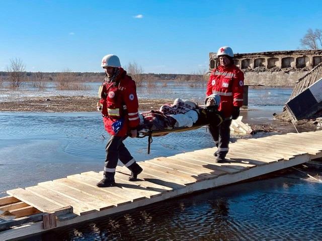 Red Cross volunteers evacuate a woman across a makeshift bridge at Demydiv, Ukraine. (Credit...