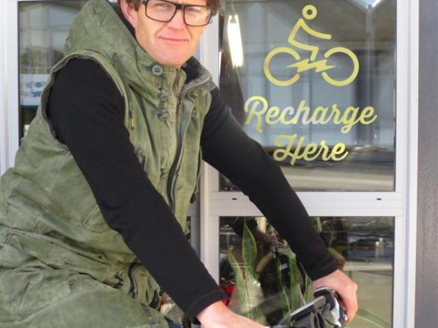 Charge About director Campbell Read with one of his eBikes at a charging station. Photo supplied.