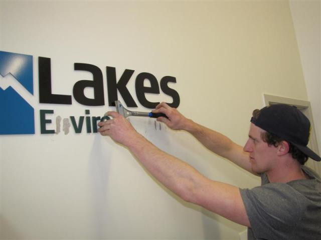 Connor Harrison, of Sign It Signs, removes Lakes Environmental signs from the authority's office...