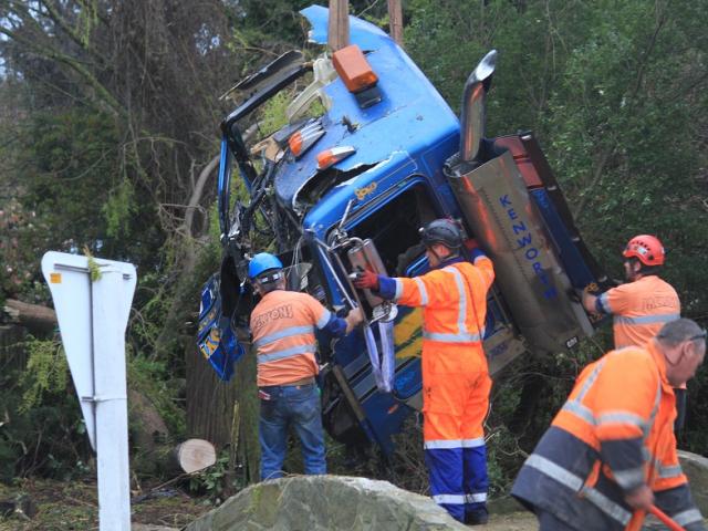 Crews work to remove the cab of the tanker after the crash. Photo: Hamish MacLean