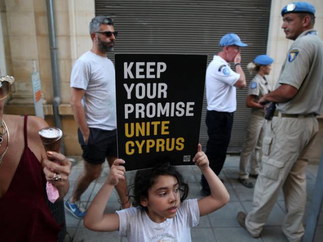 A girl holds a placard during a demonstration in favour of a peace settlement between Greek and...