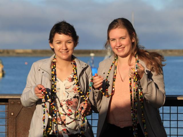 Sisters Hailey (left), and Tyla Crossan  hold a necklace made of beads that represent  every...