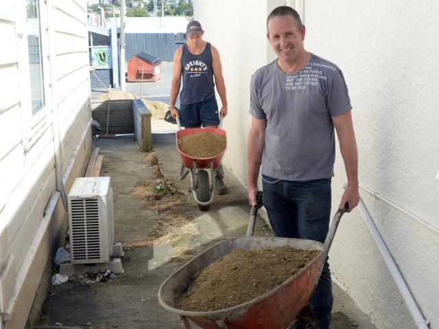 Property owner Phil Seaton (front) and Steve Green wheelbarrow loads of fill at Mr Seaton's...