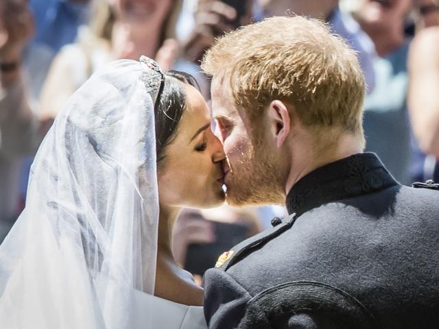 Prince Harry, Duke of Sussex, and Meghan Markle, Duchess of Sussex, kiss on the steps of St...