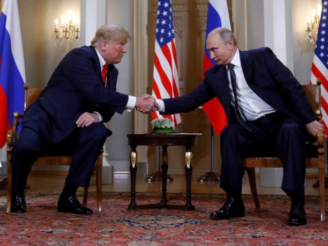 US President Donald Trump and Russia's President Vladimir Putin shake hands as they meet in...