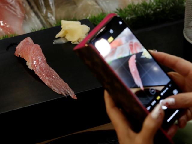A customer takes pictures of a plate of food prepared from the tuna. Photo: Reuters