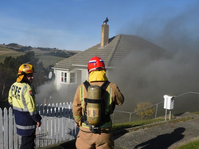 Smoke billows from a home in Puketai St, Andersons Bay, yesterday after a compost pile containing...