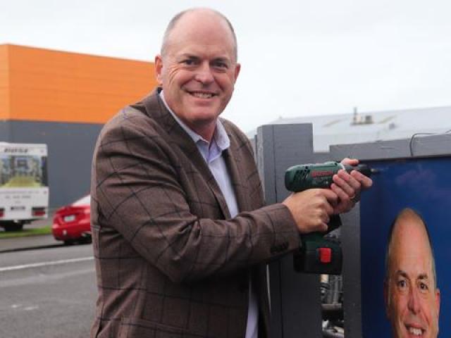 Todd Muller places the final screw in the new billboard. Photo: RNZ / Tom Kitchin