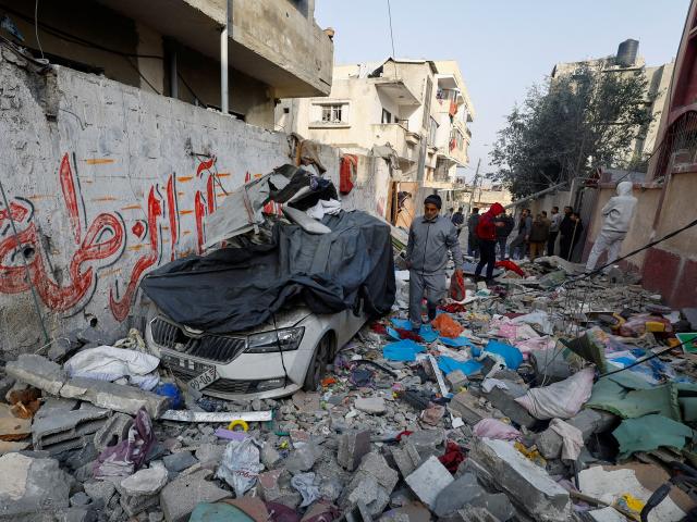 Palestinians inspect the site of an Israeli strike on a house in Rafah in the southern Gaza Strip...