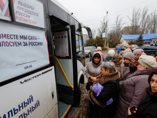 Voters gather outside a mobile polling station located in a bus, on the final day of Russia's...