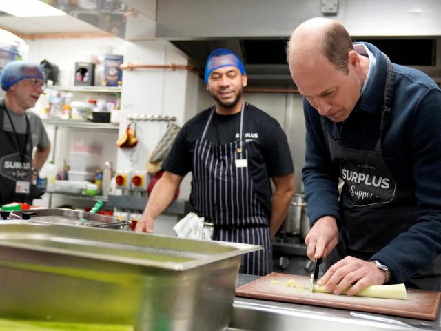 Prince William helps out in the kitchen during a visit to Surplus to Supper, a food...