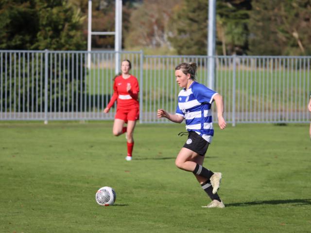 Wyndham Town player Freya Bols collects a pass, dribbles the ball about 15m and then boots it...