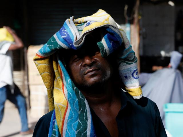A man uses a towel to protect his head from the heat on a hot summer day in New Delhi on Tuesday....
