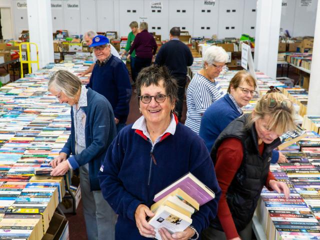 Bookarama volunteers sort through tens of thousands of books while Jacquie Webby carries a...
