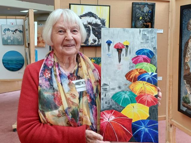 Holding her oil painting of umbrellas called It’s Raining Again is Norma Parks, of Tapanui. The...
