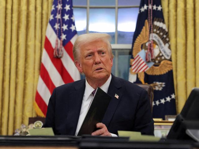 US President Donald Trump signs documents as he issues executive orders and pardons at the White...