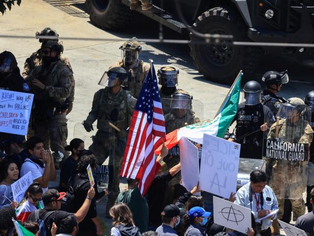 Police and members of the California National Guard stand next to demonstrators during a protest...