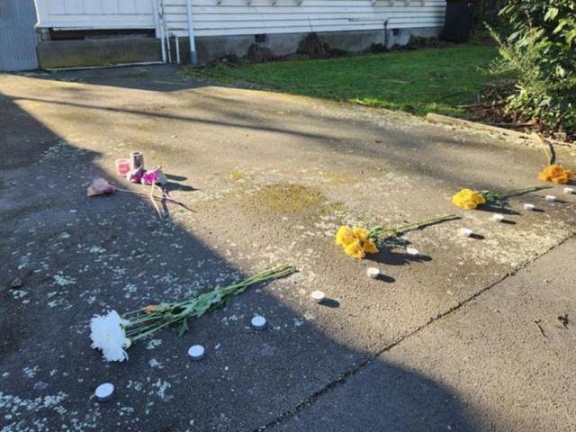 Flowers and candles laid on the driveway of a property on Gracefield Ave, where police found...
