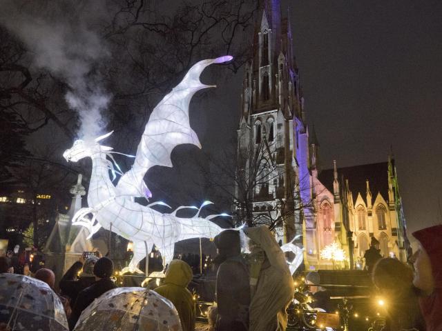 A glowing dragon exhales a smoke cloud over visitors eagerly waiting to be let into the Dunedin...