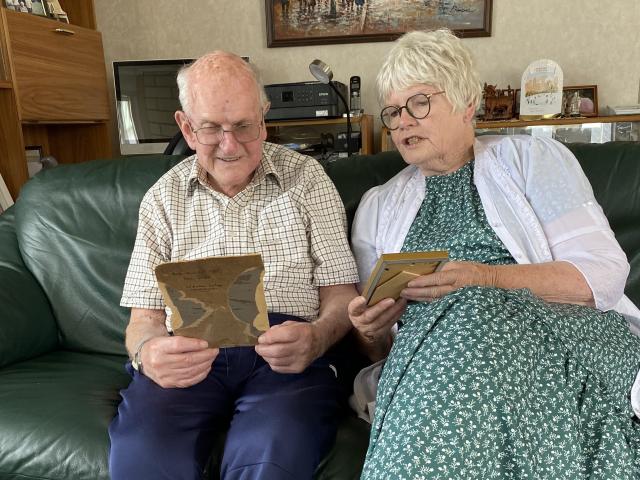 Noel Dickel and Faye Ormandy look at the photo of the 1921 relay team wearing their medals. PHOTO...