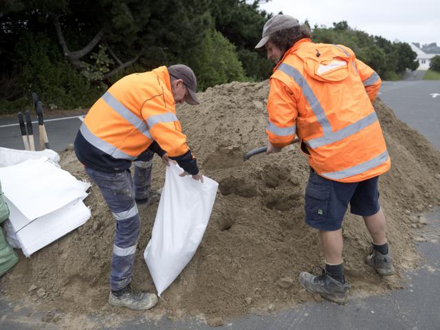 Delta employees Peter Soper (left) and Simon Smaill fill a sandbag at the Dunedin Ice Stadium...