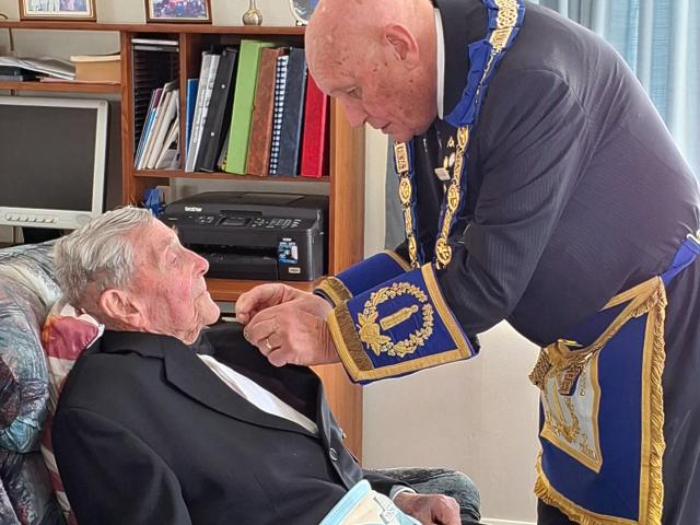 Junior grand warden Paul Johnston pins a 60-year service bar on to past master Owen Soal. PHOTO:...