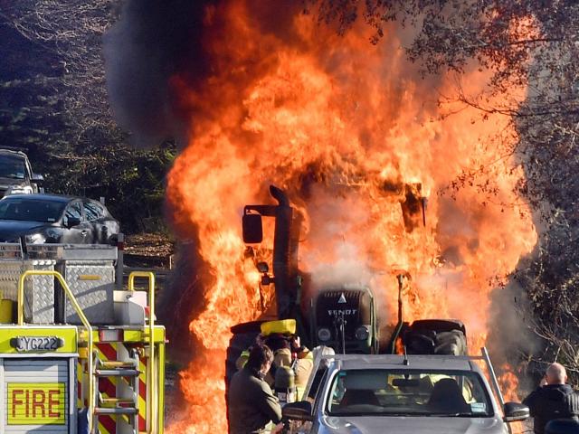 A hedge-cutting tractor is engulfed in flames in Three Mile Hill Rd yesterday. Photos: Stephen...