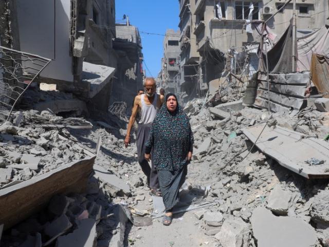 Palestinians walk amid rubble after an Israeli strike hit an evacuated residential building at...