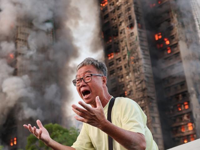 A distraught resident Wong, 71, reacts after claiming his wife is trapped inside the complex....