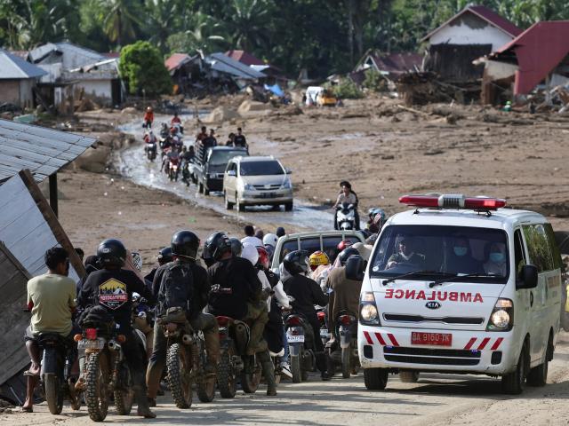 An ambulance drives through an area hit by flash floods in Palembayan in Indonesia's West Sumatra...