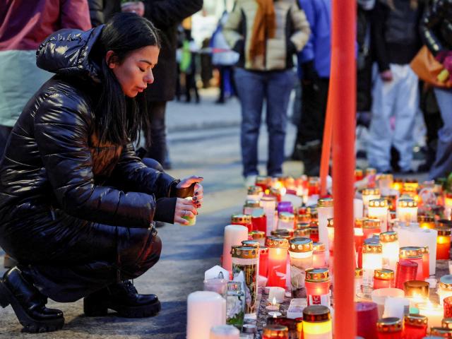 A woman places a candle outside the "Le Constellation" bar in Crans-Montana after the deadly fire...