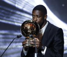 Ousmane Dembele kisses the Ballon d'Or trophy after being named the winner at the awards held...