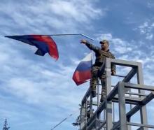 A member of the Ukrainian troop brings down a Donetsk Republic flag hoisted on a monument in...