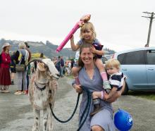 Alice Perry, of Weston, carries Ella, 3, and Ollie Harvey, 1, while wrangling Ralph the goat, 4,...