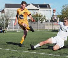 Universities defender Max McGuinness makes a clearance under pressure from Christchurch United's...