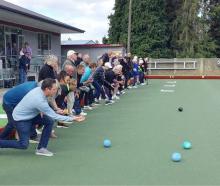 Te Anau Bowling Club members give the club’s new artificial green a test roll. PHOTO: SUPPLIED