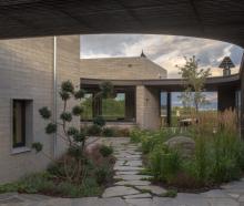 A casual meander over stone pavers links a sequence of gardens to a spacious central courtyard at...