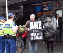 Climate protesters, holding signs and dressed as a piece of coal, talk to police. PHOTO: STEPHEN...