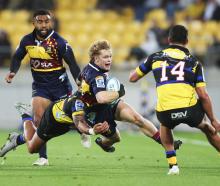 Finn Hurley of the Highlanders is tackled by Billy Proctor of the Hurricanes during tonight's...