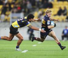 Highlanders fullback Finn Hurley tries to dance around Hurricanes centre Billy Proctor in...