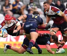 Harry Wilson of the Reds is tackled during today's Super Rugby Pacific match against the...