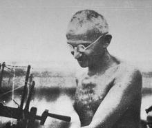 Mohandas Karamchand Gandhi, known by the honorific title Mahatma, demonstrates spinning with a...