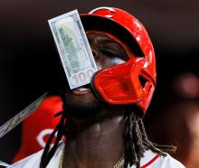 Cincinnati Reds shortstop Elly De La Cruz is showered with fake money after hitting a solo home...