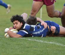 Kaikorai winger Rico Fisher scores under the tackle of AU’s Sam Berry (obscured) and Manueli...