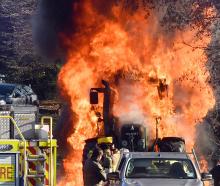 A hedge-cutting tractor is engulfed in flames in Three Mile Hill Rd yesterday. Photos: Stephen...