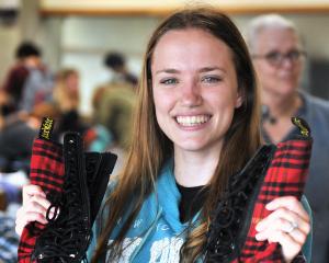 Holding a pair of near-new Doc Marten shoes bought for less than 50c is University of Otago...
